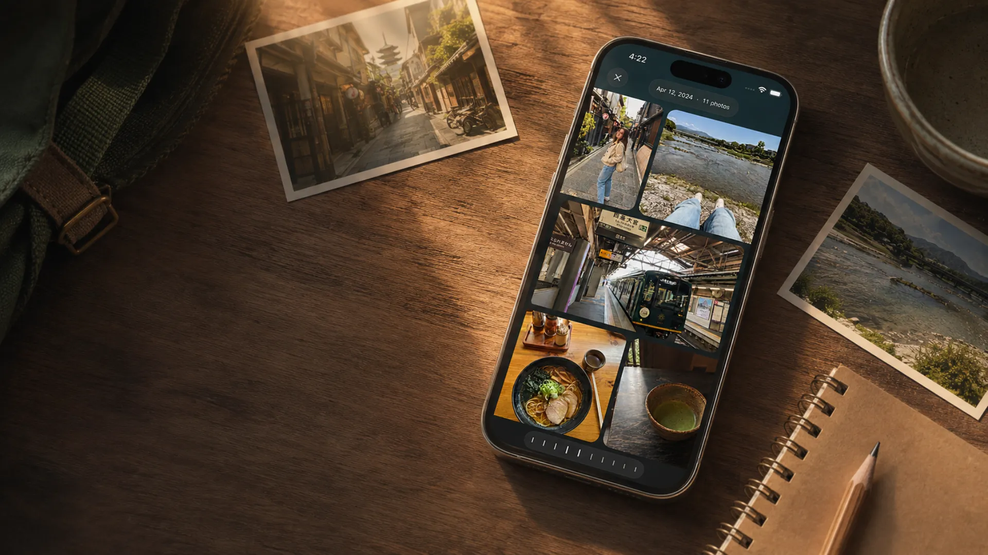 An iPhone on a wooden desk showing a day of Kyoto photos, printed photos scattered around it.